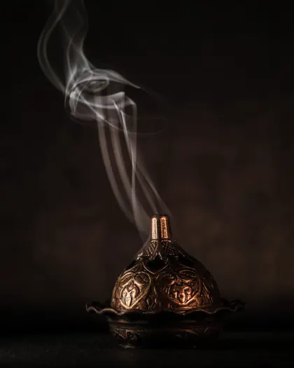A small copper burner with a thread of smoke rising
