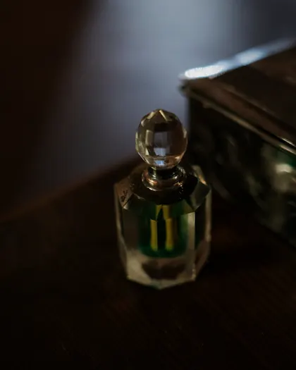 A crystal oil bottle beside a silver box in low light