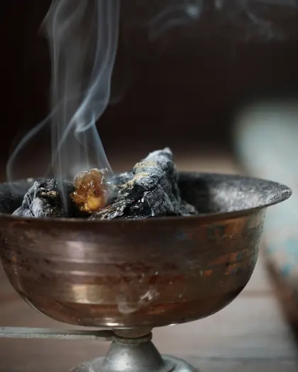 Oud and resin smouldering on coal in a copper bowl