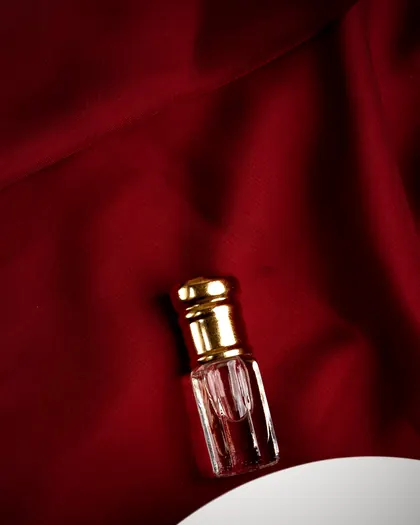 A small oil bottle with a gold cap on red silk