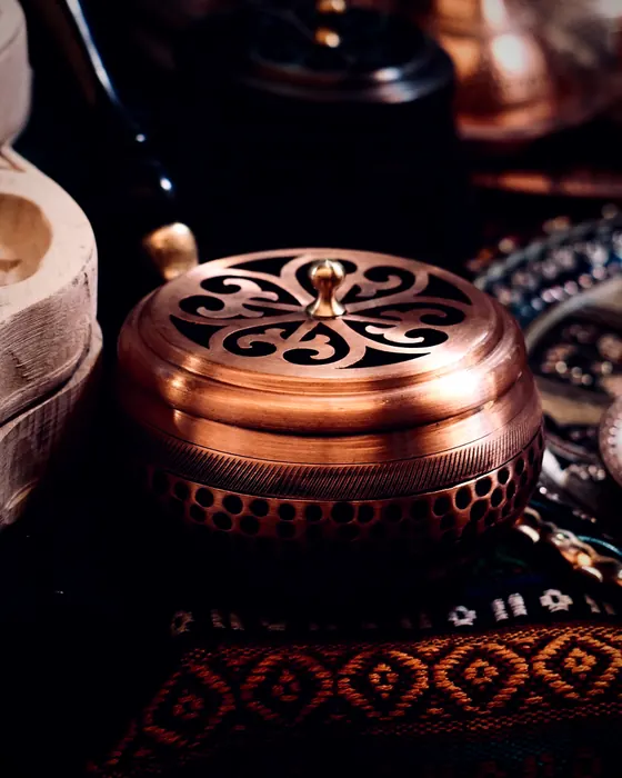 An engraved copper burner on a red Sadu rug in the house majlis